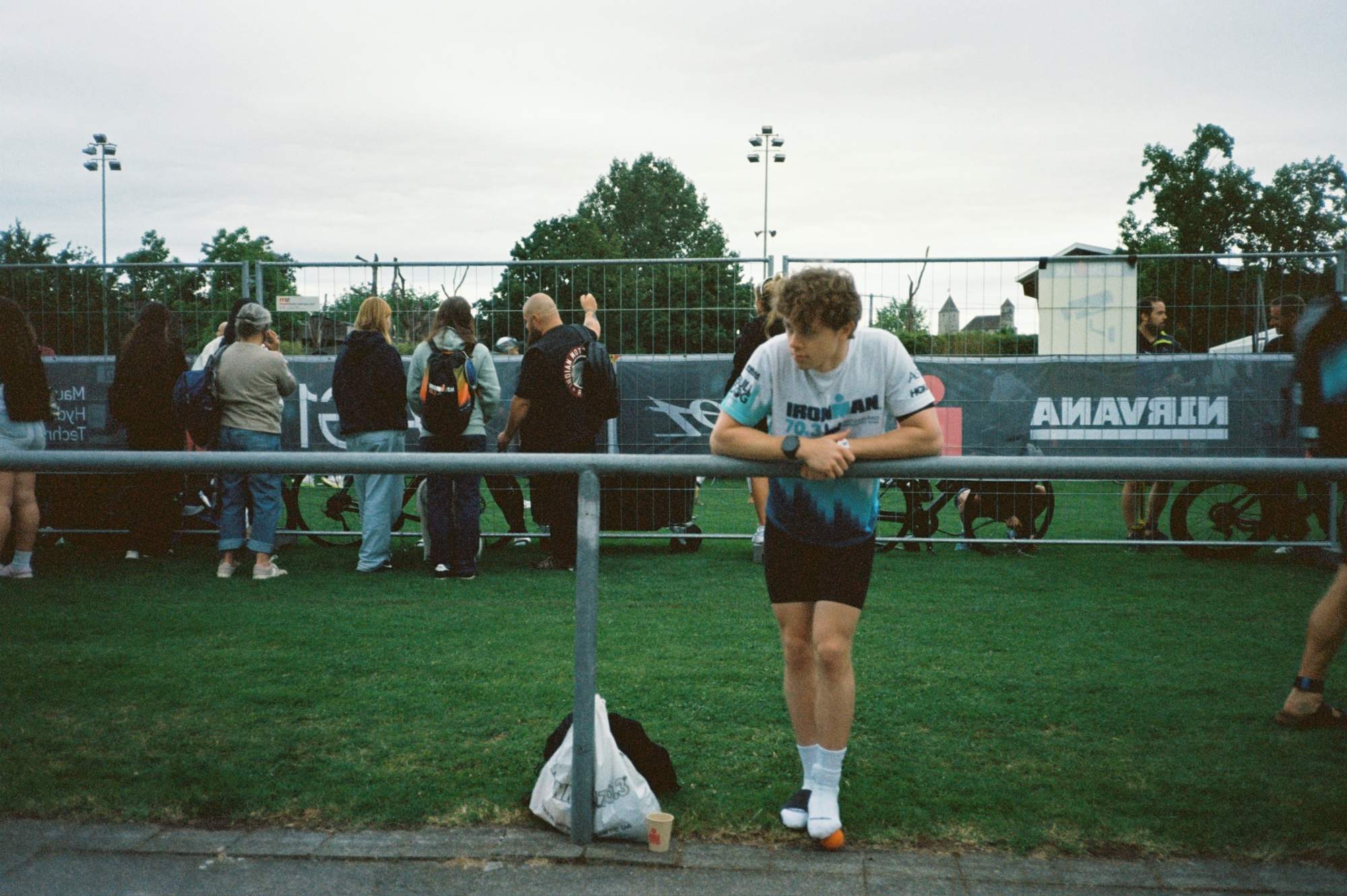 Aidan in an IRONMAN 70.3 shirt, leaning on a railing at the race site